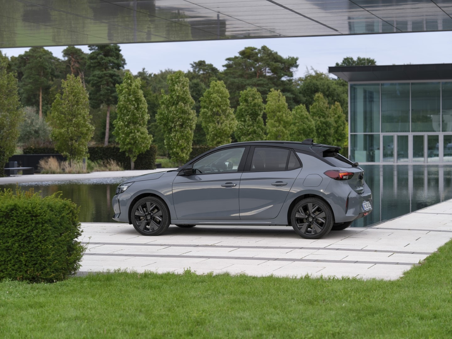 Imagen lateral del Corsa-e junto a arquitectura moderna, subrayando su diseño contemporáneo.