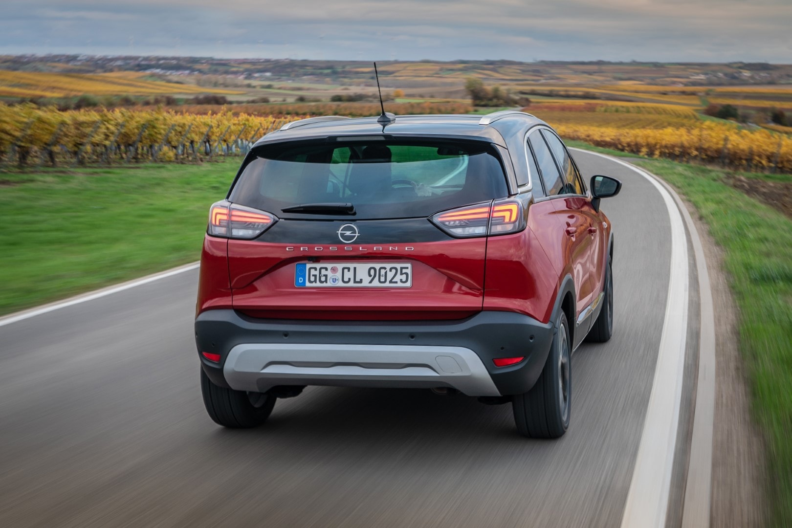 Imagen trasera del Opel Crossland en un camino rural al amanecer.