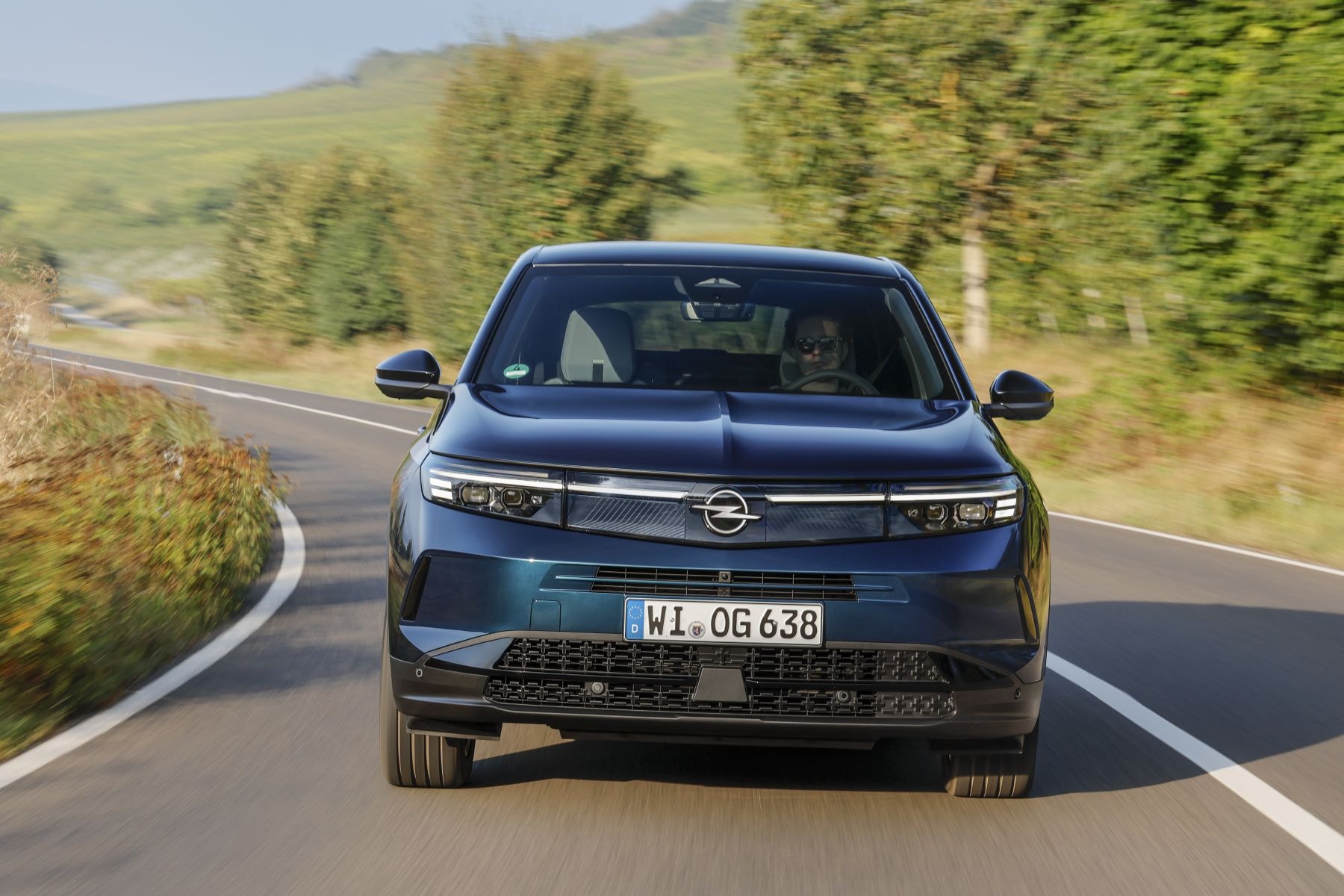El Grandland Híbrido en movimiento, con un fondo de paisajes otoñales