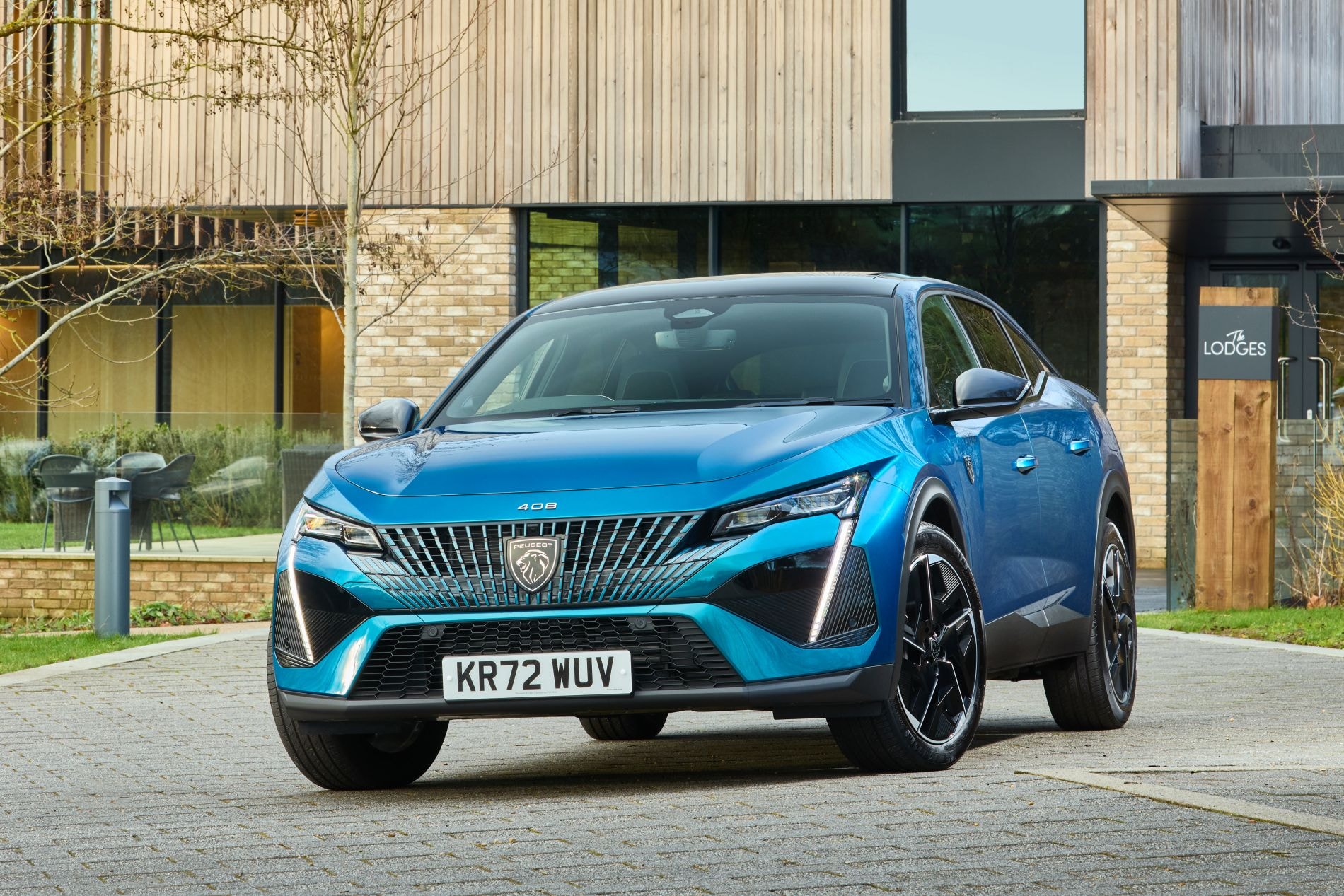 Peugeot 408 estacionado frente a un moderno edificio.
