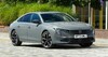 Vista lateral y delantera del Peugeot 508, resaltando su aerodinámica y diseño moderno. Vista lateral y delantera del Peugeot 508, resaltando su aerodinámica y diseño moderno.