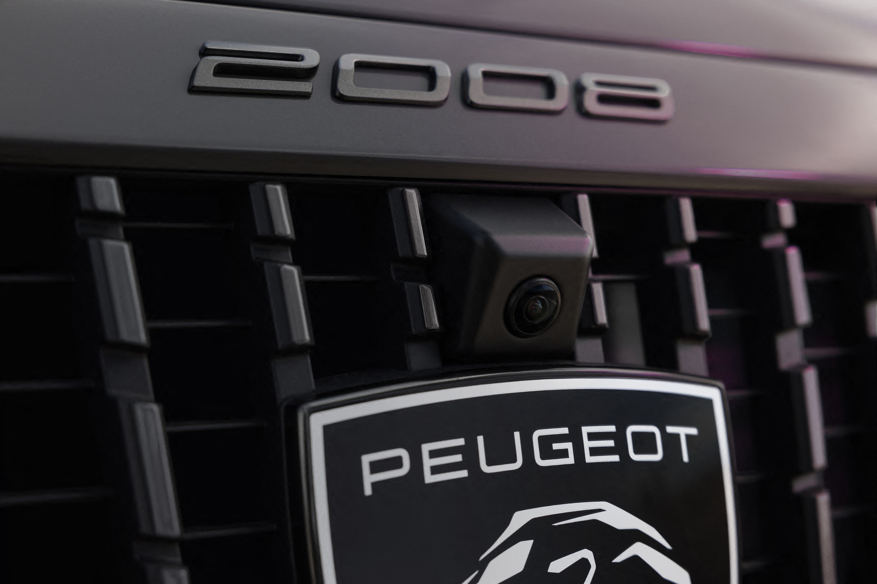 Vista cercana de la parrilla frontal con cámara y emblema Peugeot e-2008.