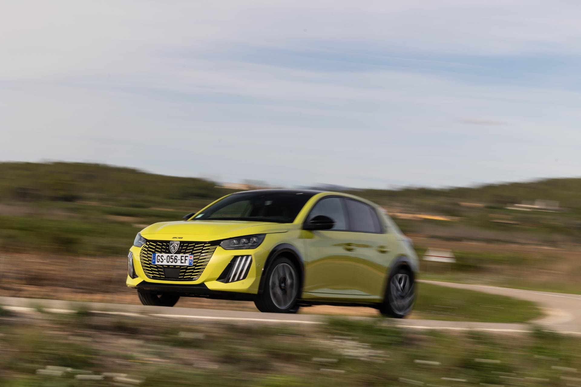 Vista lateral del Peugeot e-208 en movimiento, destacando su dinamismo.