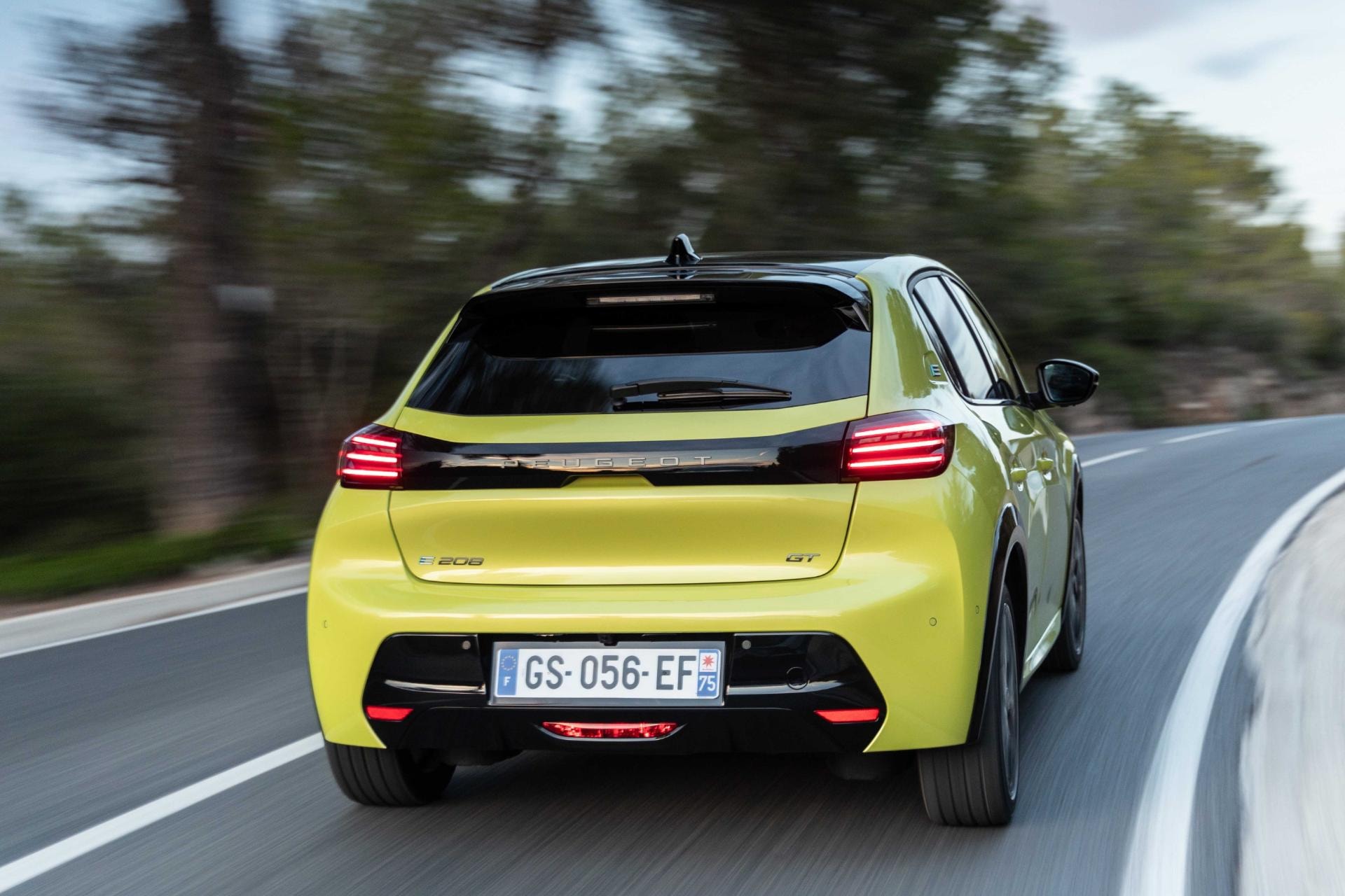 El Peugeot e-208 capturado en movimiento, destacando su agilidad y diseño posterior.