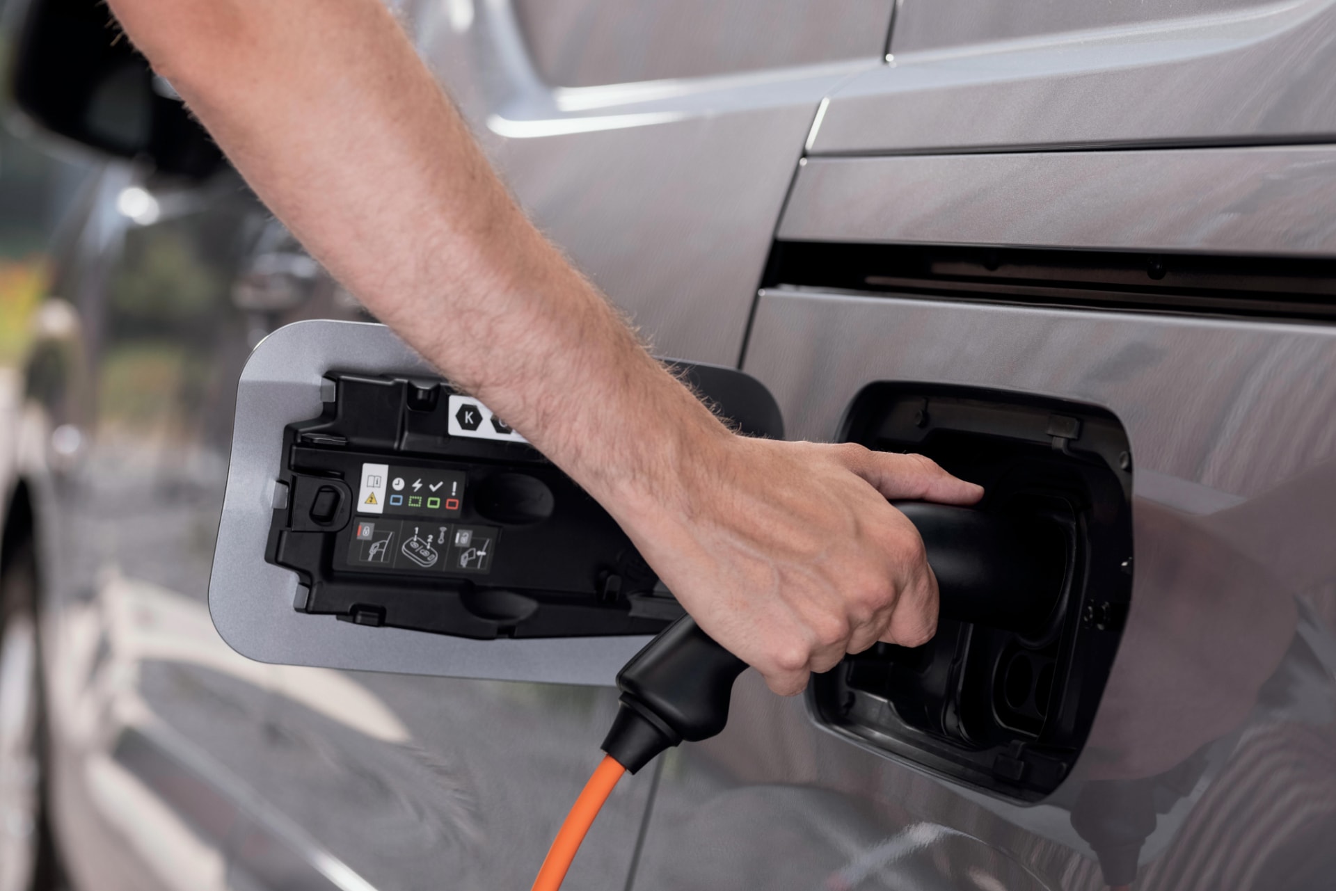 Proceso de carga eléctrica del Peugeot e-Rifter, mostrando el enchufe y la tapa de carga.