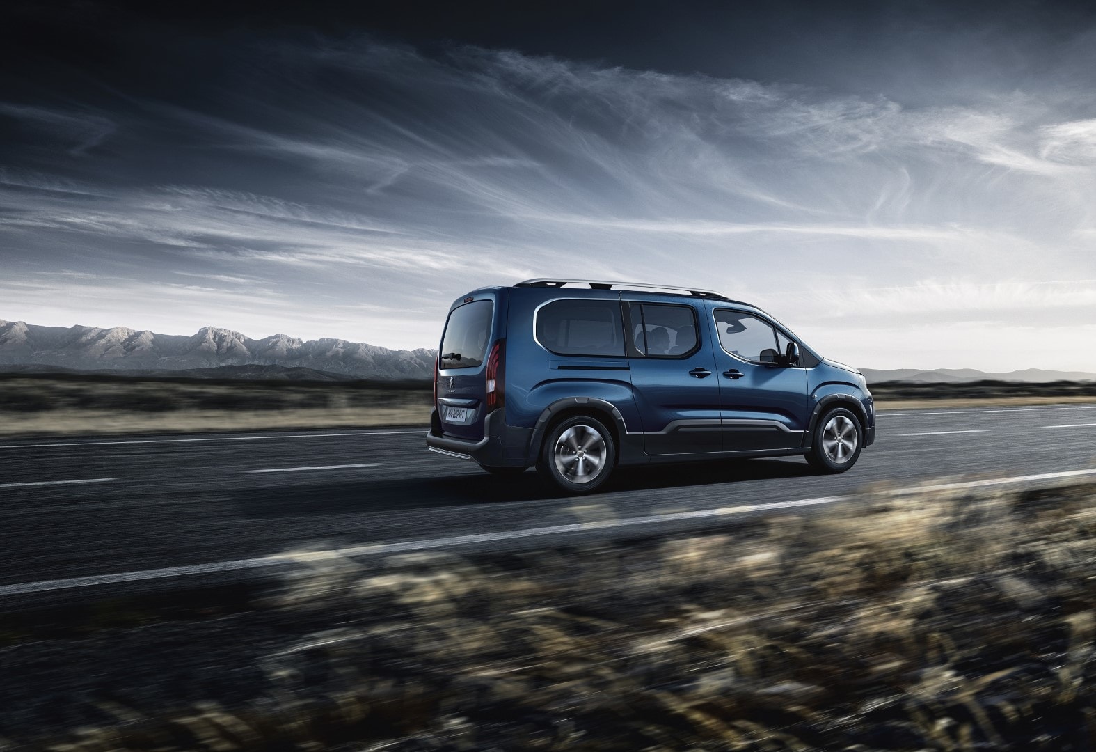 Perspectiva trasera del Peugeot Rifter en una carretera solitaria, simbolizando libertad.