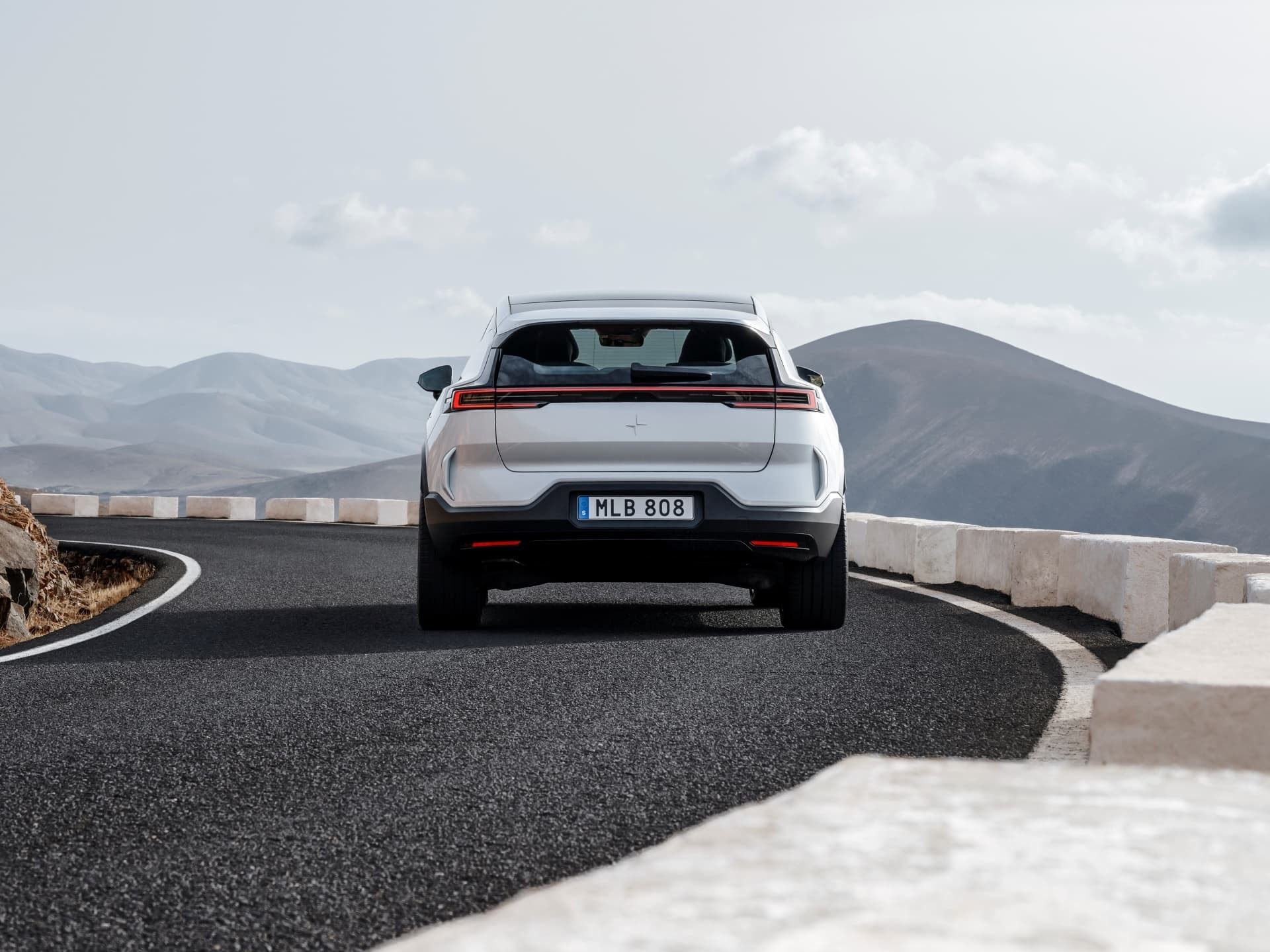 Vista trasera del Polestar 3 en carretera, destacando su diseño de luces LED distintivo.