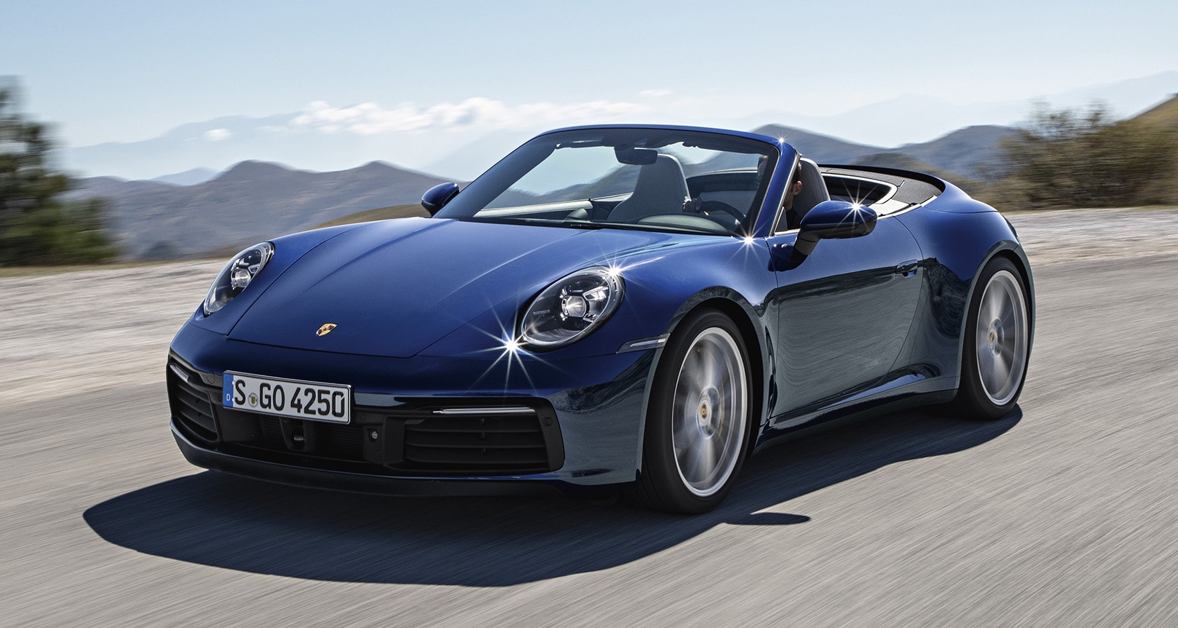 Vista dinámica del Porsche 911 Cabrio en carretera, realzando su diseño deportivo.