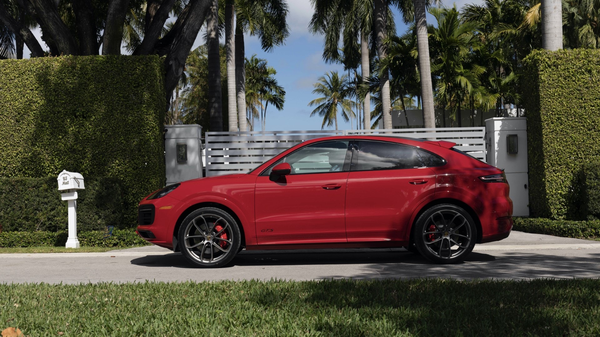 El Cayenne Coupé luce su diseño lateral con un paisaje ajardinado.