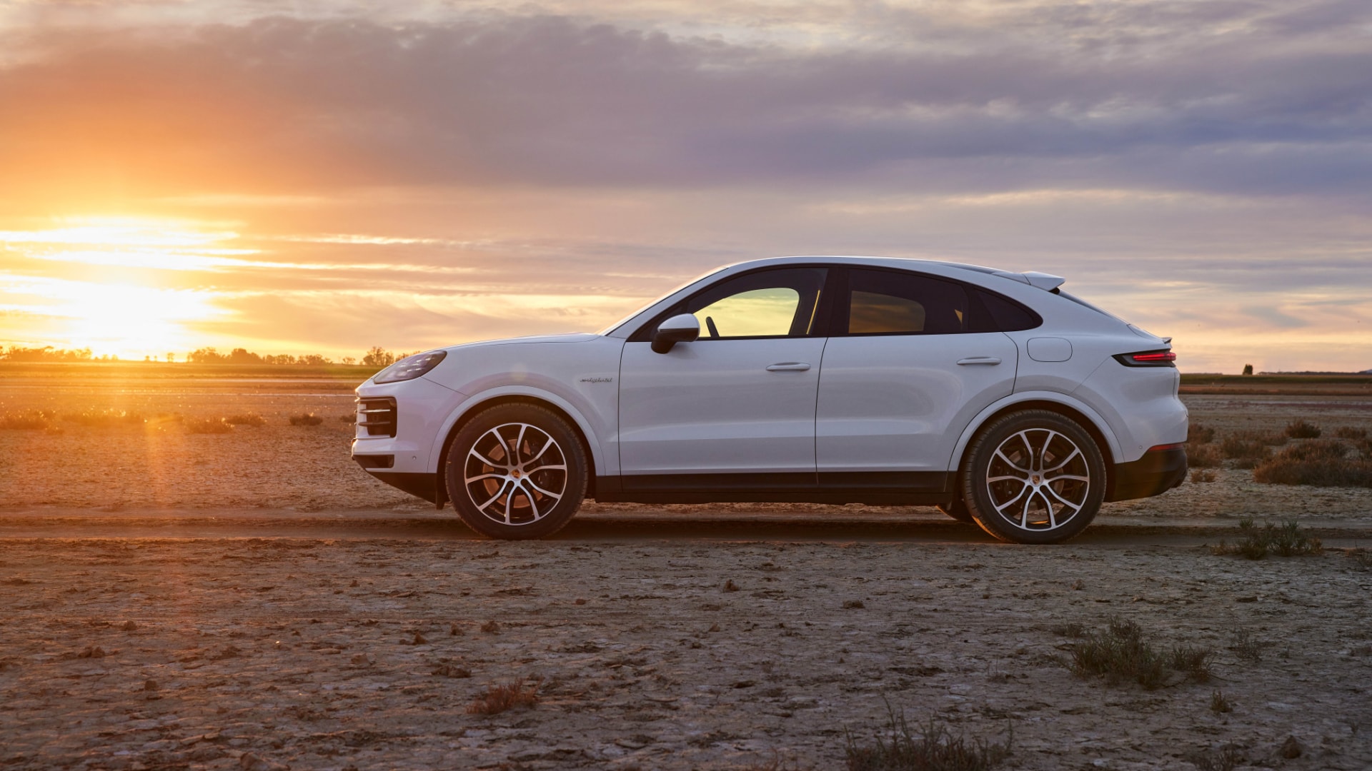 Perfil del Porsche Cayenne S Hybrid al atardecer. Dinamismo y diseño robusto.