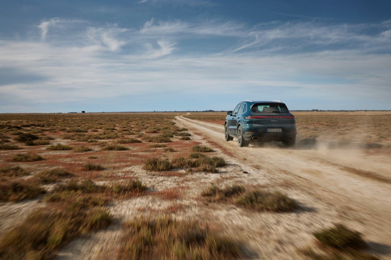 Porsche Cayenne recorriendo terreno árido a alta velocidad.