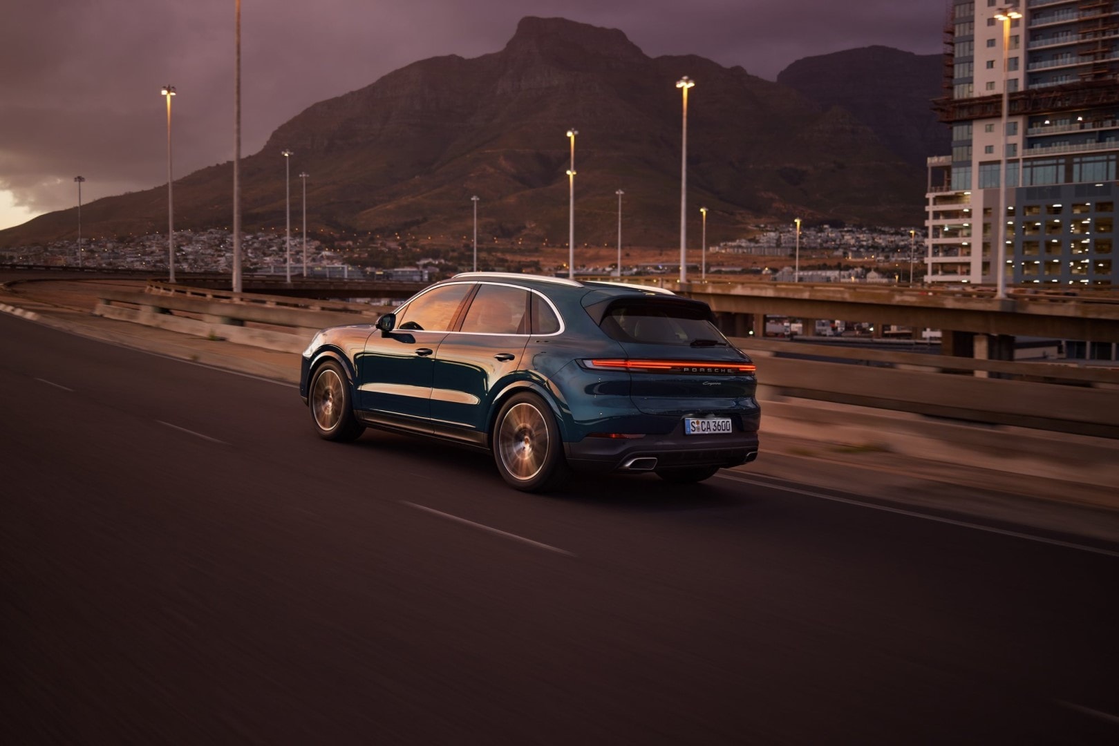 Perfil lateral del Porsche Cayenne circulando por la ciudad de noche.