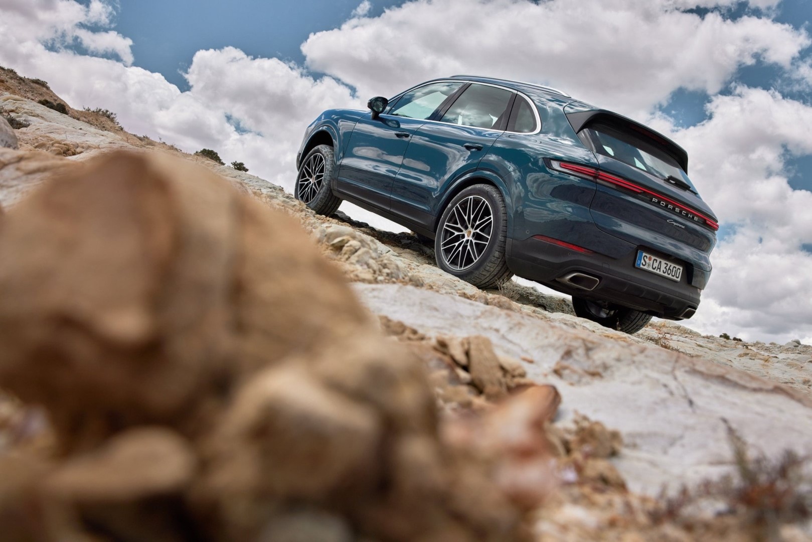 Imagen del Porsche Cayenne escalando rocas, demostrando su capacidad todoterreno.