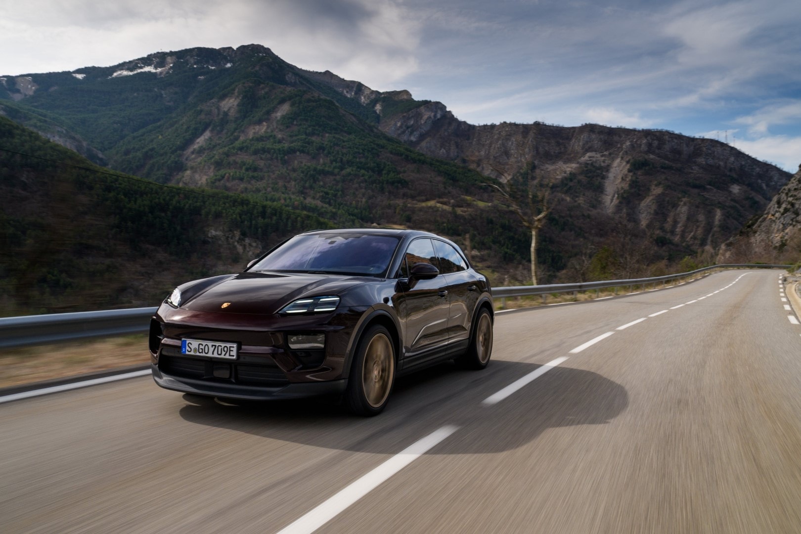 Captura del Porsche Macan desde el frente mientras recorre una carretera de montaña, enfatizando su carácter aventurero.