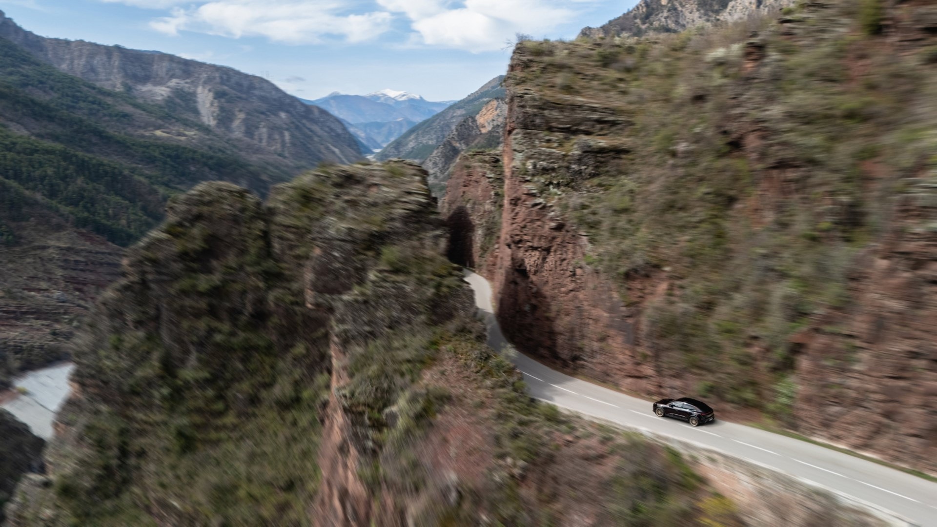 Vista lateral de un Porsche Macan en carretera de montaña, mostrando su elegancia.