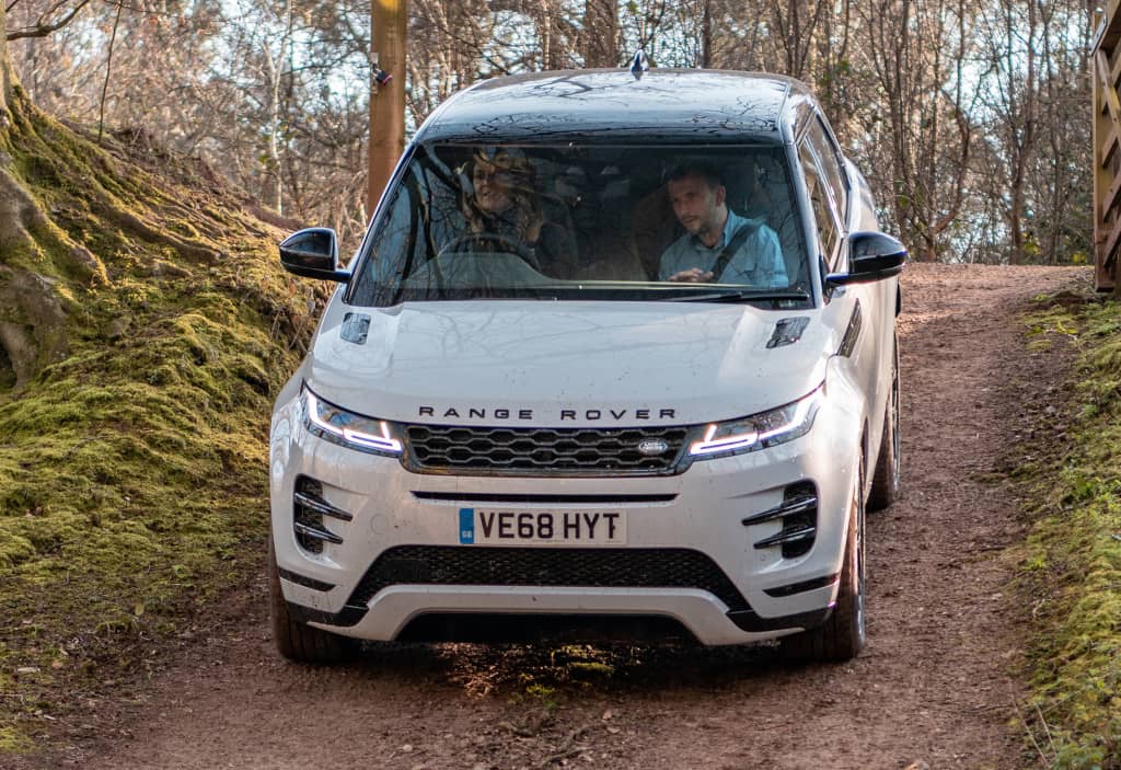 Range Rover Evoque en camino forestal, enfoque en la estética delantera.
