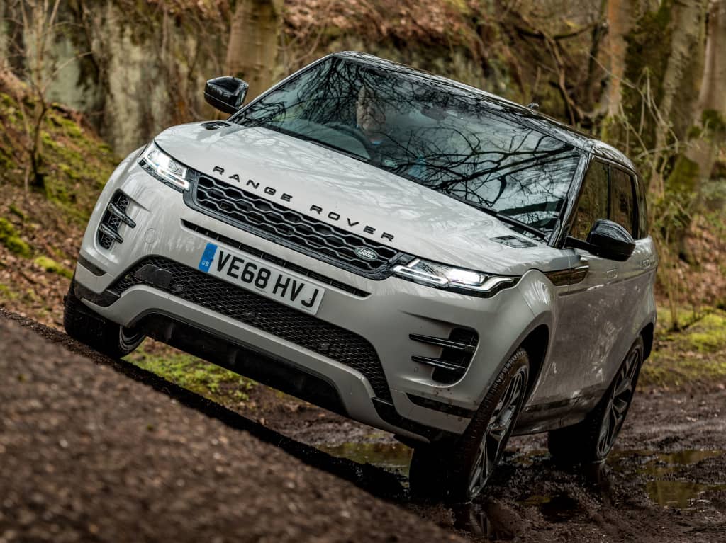 Imponente postura del Evoque híbrido en un camino forestal, vista delantera y lateral.