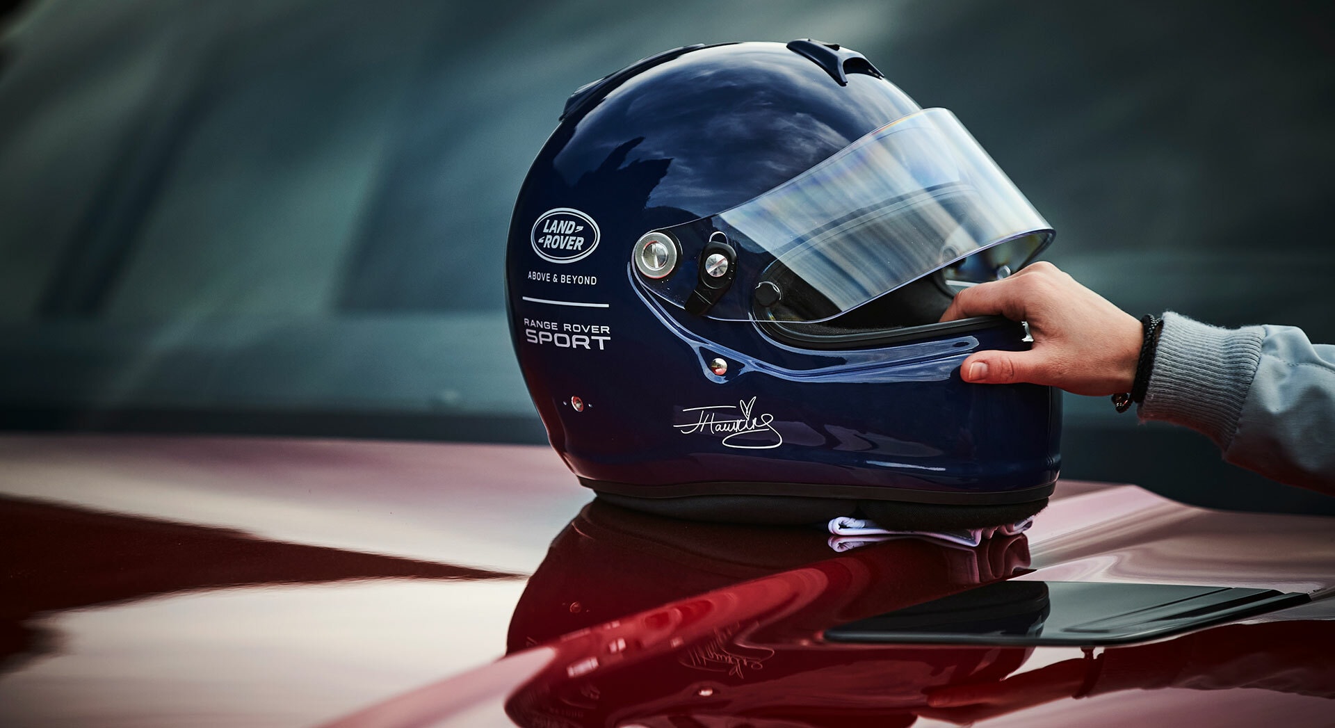 Casco de competición apoyado sobre el capó del coche.