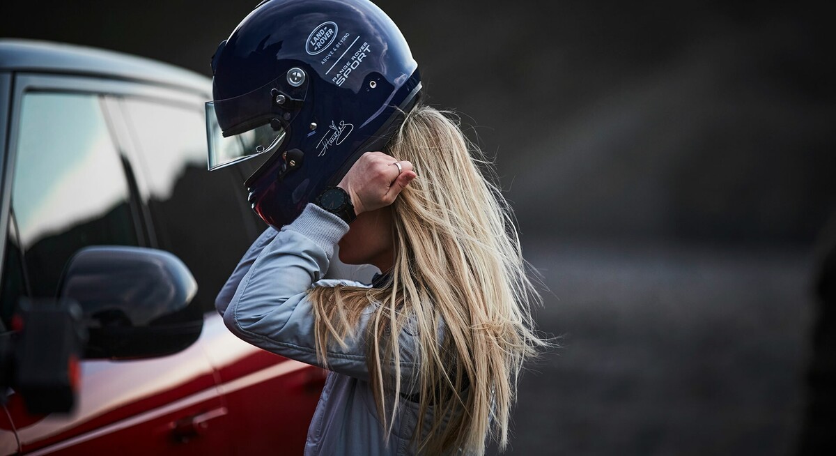 Piloto ajustando su casco junto al coche, preparación intensa. Piloto ajustando su casco junto al coche, preparación intensa.