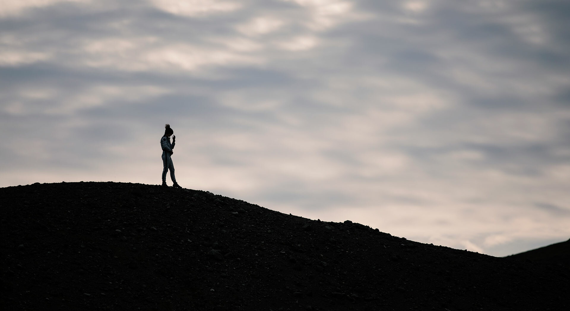 Figura humana en contraluz sobre paisaje sombrío.