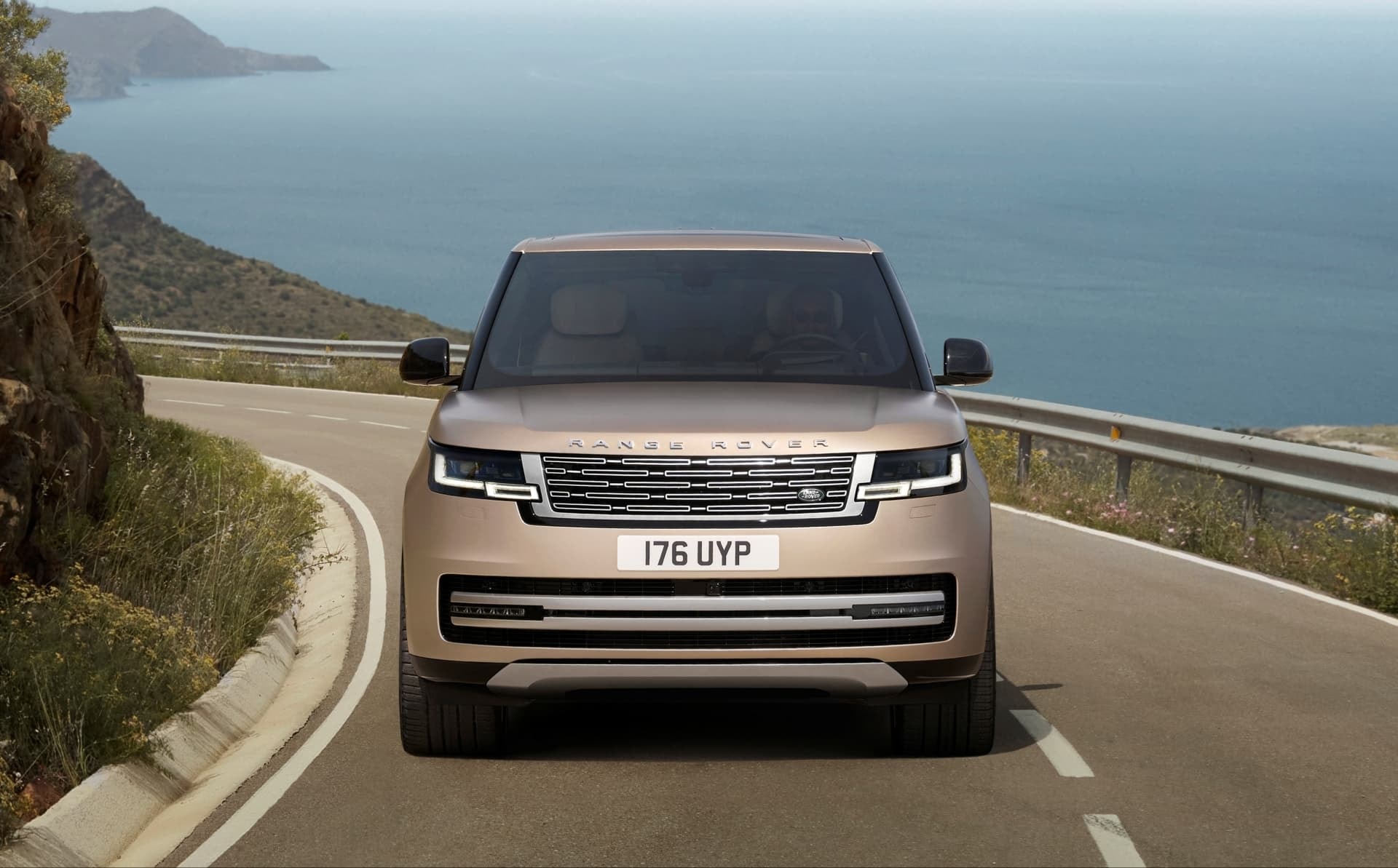 Vista frontal del Range Rover transitando una carretera con vistas escénicas.