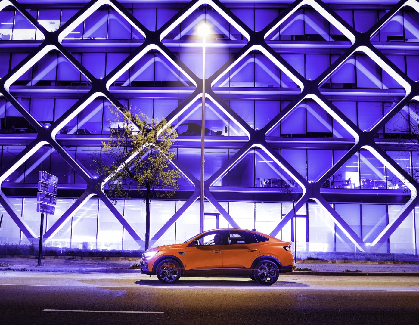 Perfil del Renault Arkana híbrido iluminado por luces urbanas nocturnas