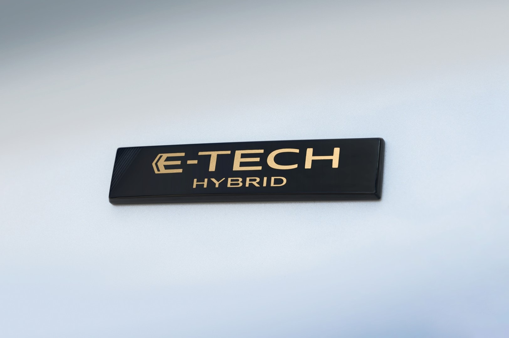 Placa E-TECH Hybrid sobre carrocería azul, detalle distintivo de la gama híbrida.