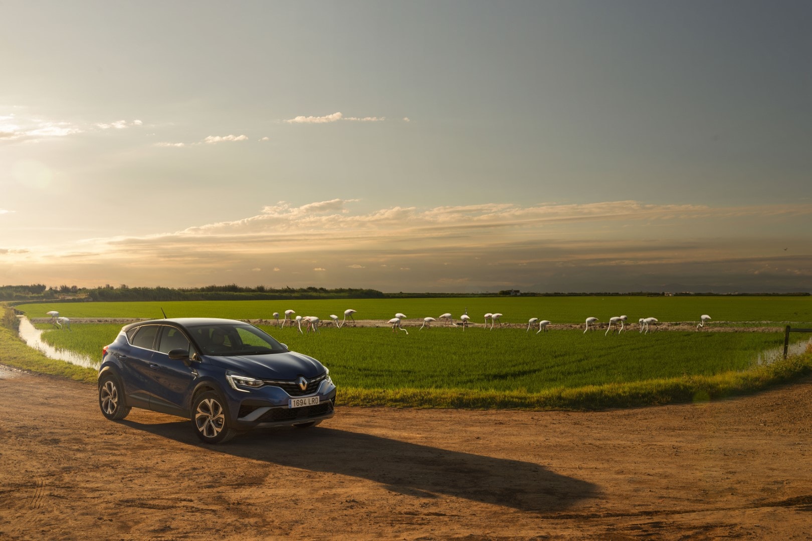 Lateral del Renault Captur híbrido en una carretera rural al atardecer