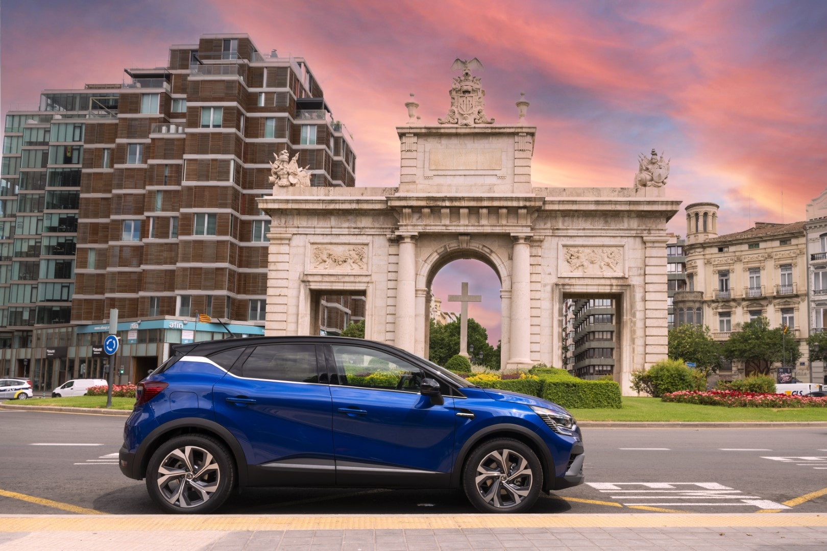 Vista lateral del Captur híbrido con un fondo arquitectónico urbano