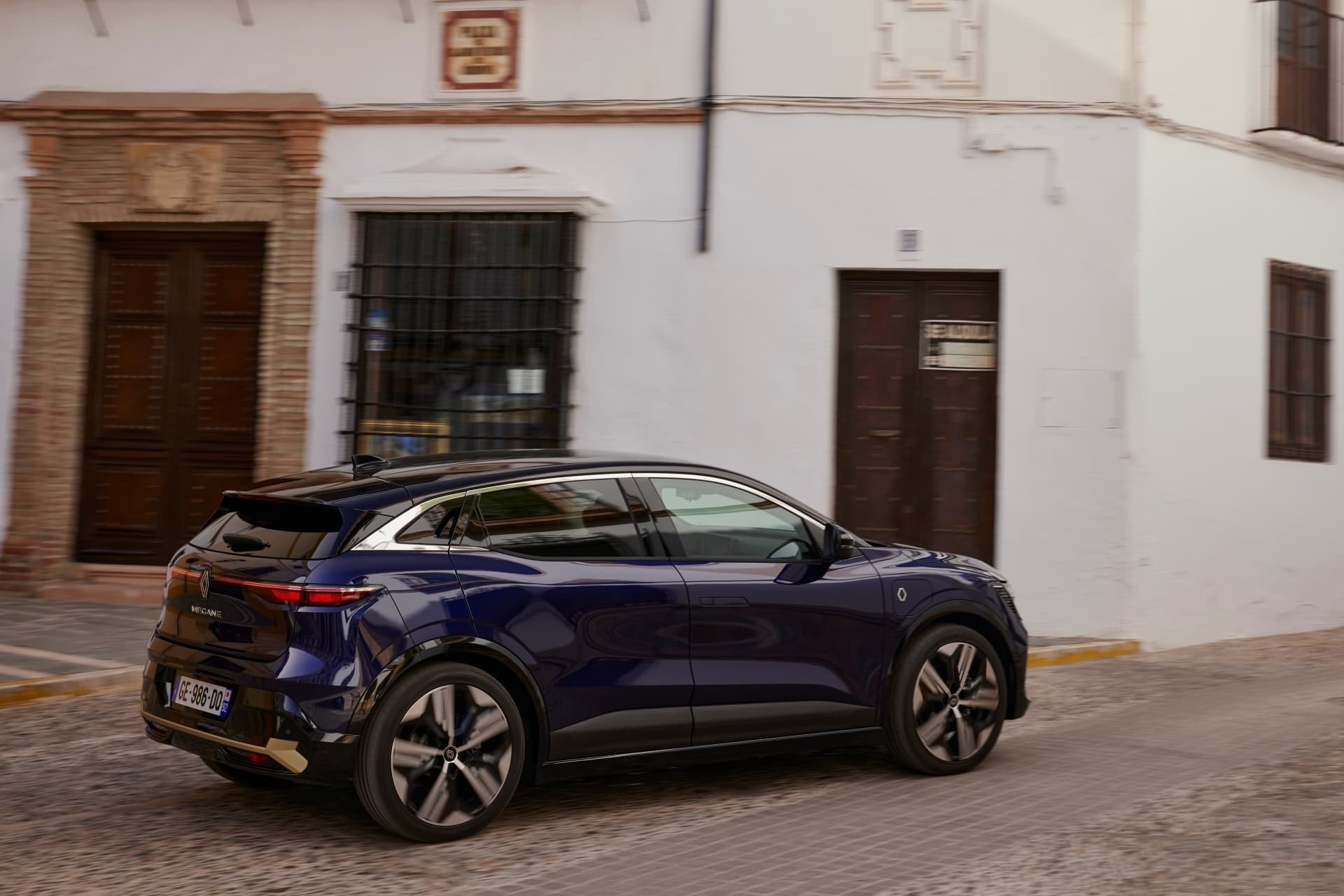 Perspectiva trasera-lateral del Mégane E-Tech eléctrico en movimiento.