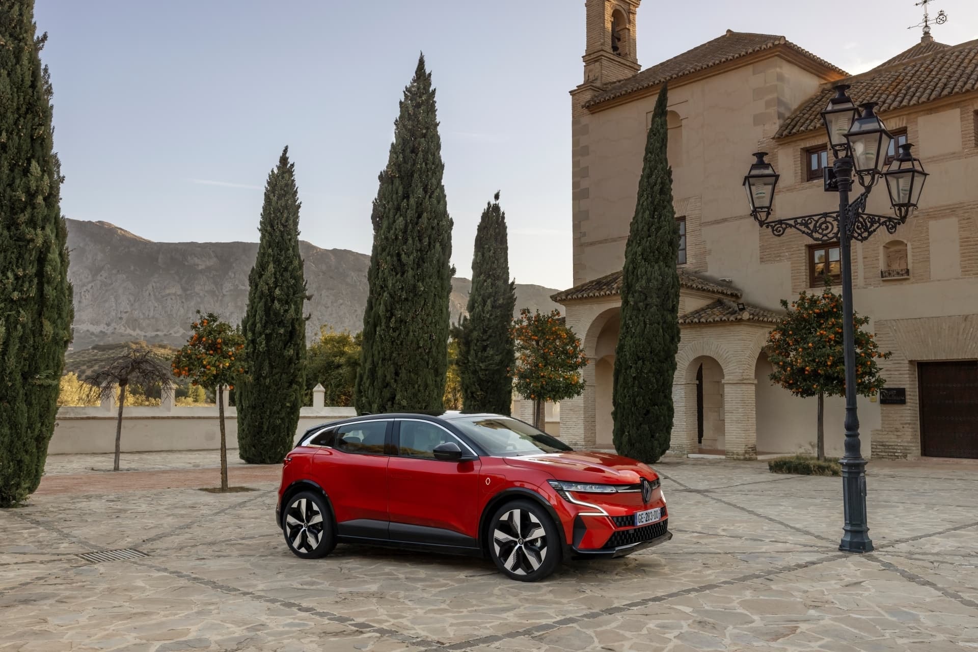 Vista lateral del Mégane E-Tech estacionado en una plaza, integrándose con la arquitectura.