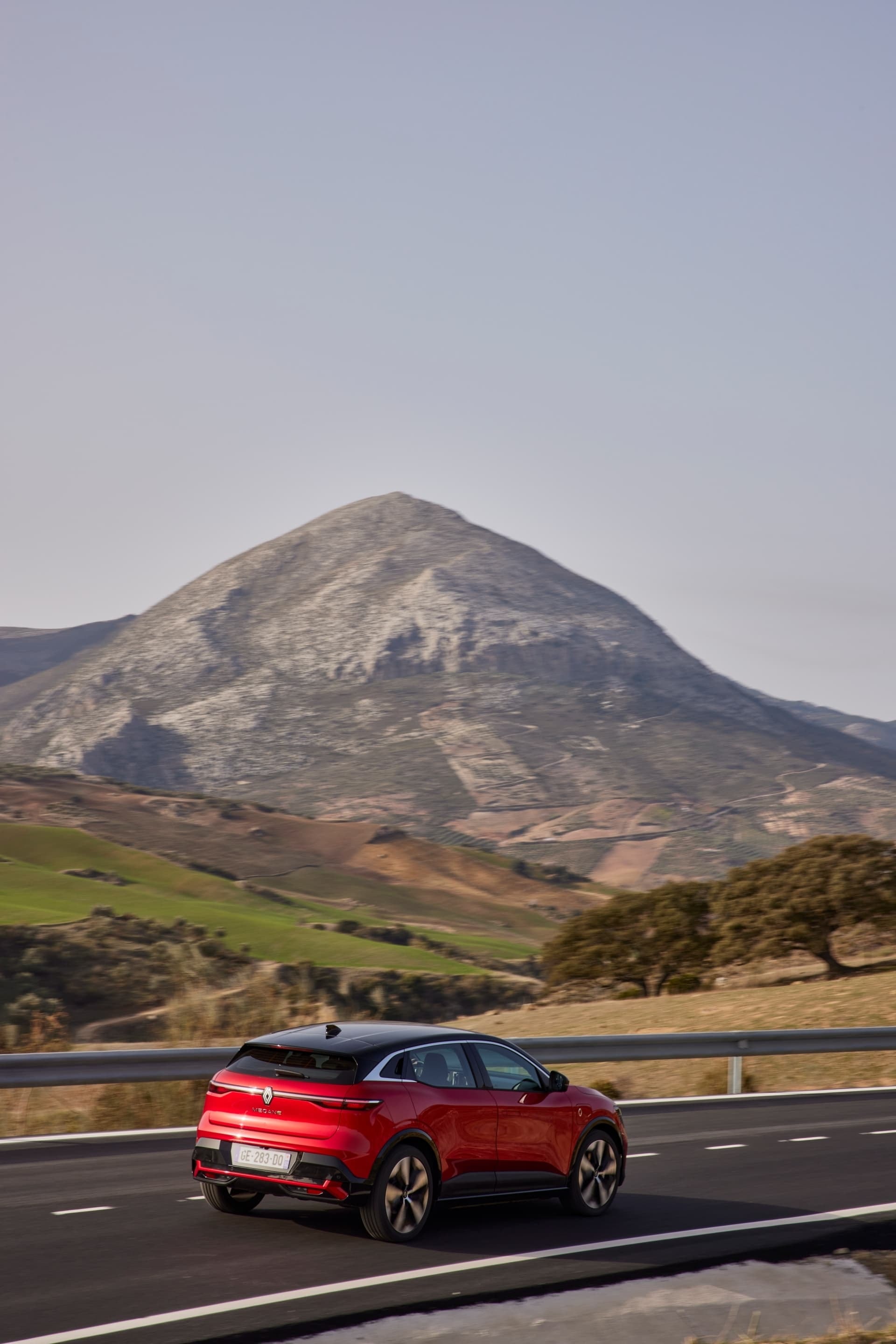 Perspectiva trasera del Renault Mégane E-Tech eléctrico con montañas de fondo.