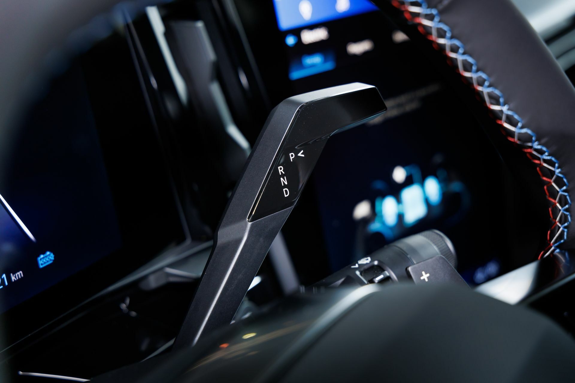 Palanca de cambios con detalles cromados y pantalla digital de fondo.