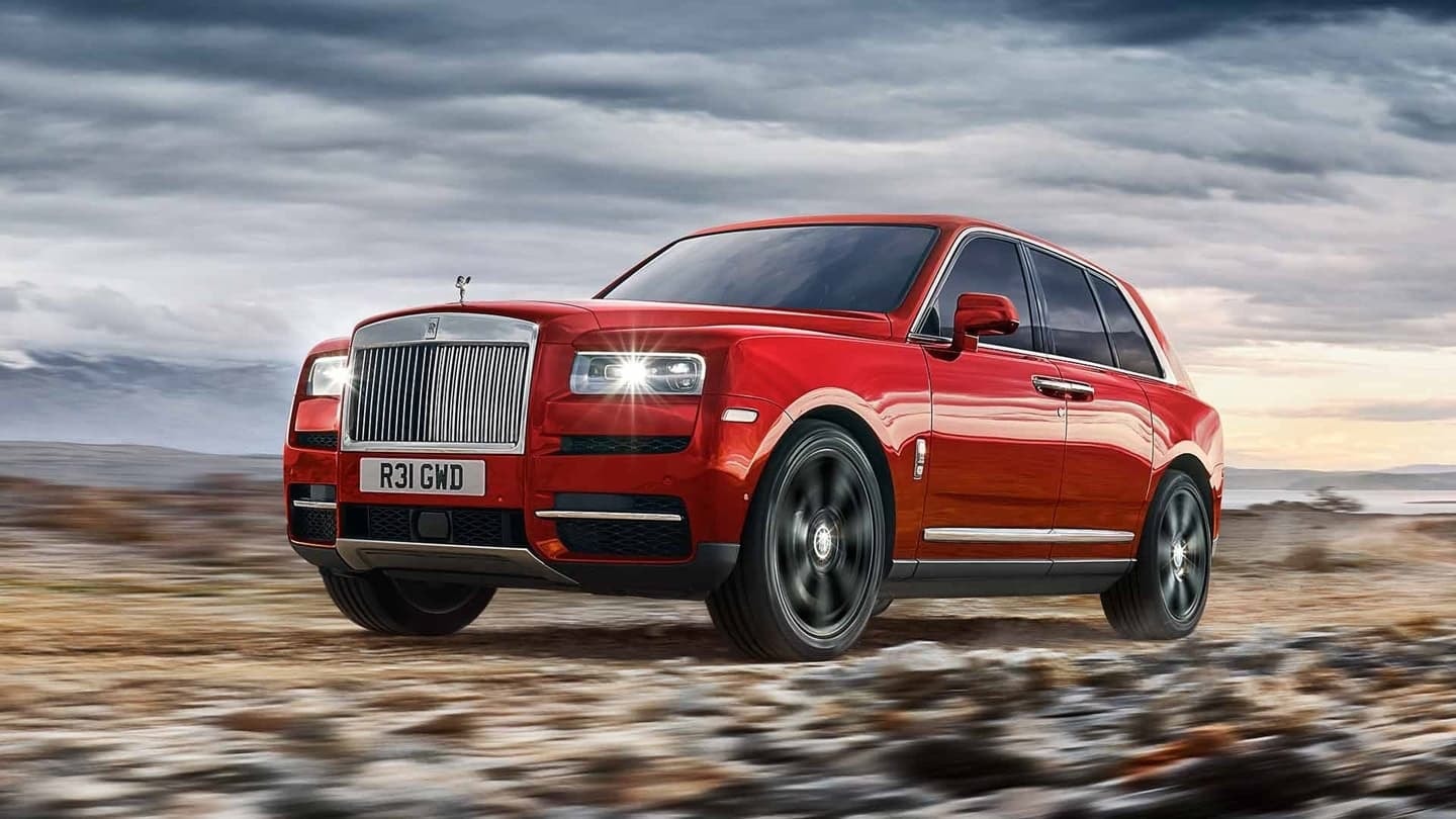 Rolls Royce Cullinan en rojo desplazándose con soltura sobre terreno árido.