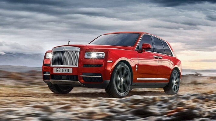 Rolls Royce Cullinan en rojo desplazándose con soltura sobre terreno árido. Rolls Royce Cullinan en rojo desplazándose con soltura sobre terreno árido.