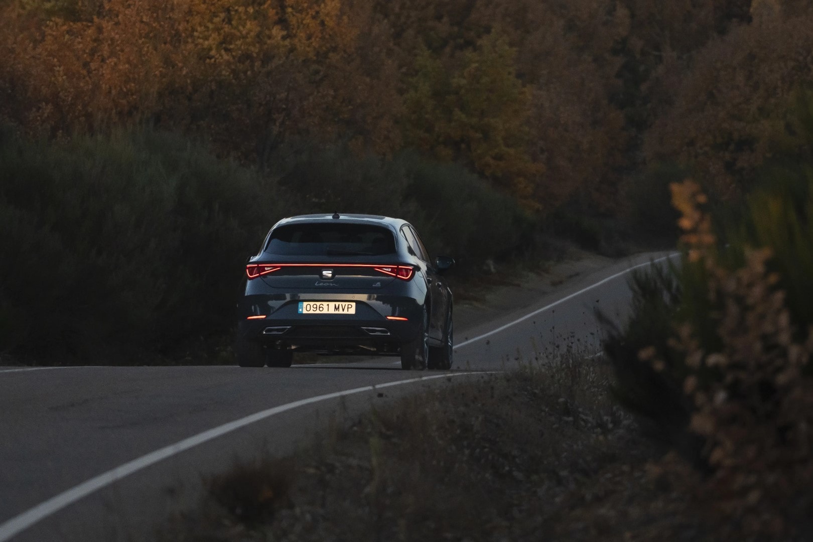 SEAT León Híbrido rojo, con fondo arquitectónico moderno.