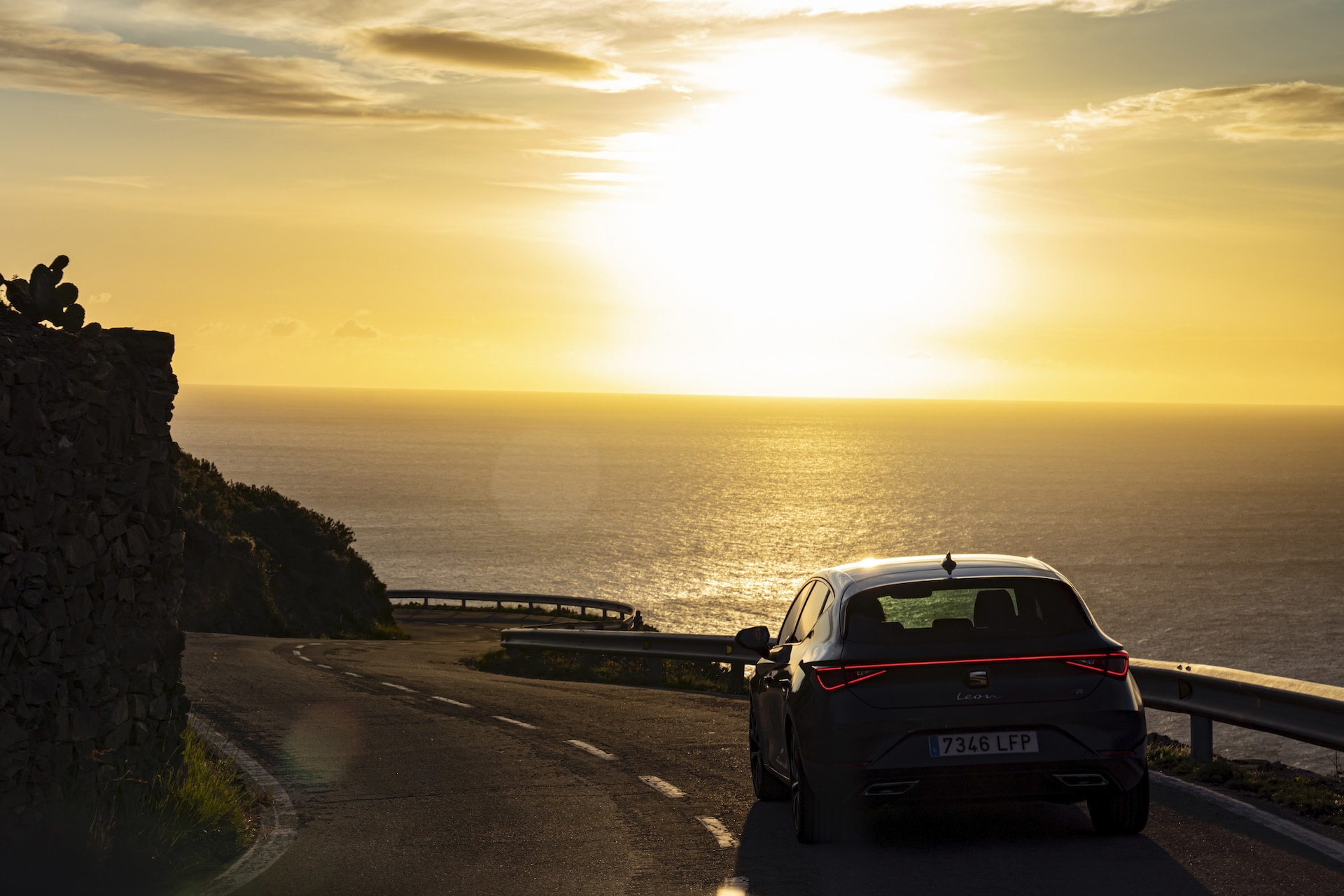 Vista lateral del SEAT León en una carretera costera, resaltando su diseño.