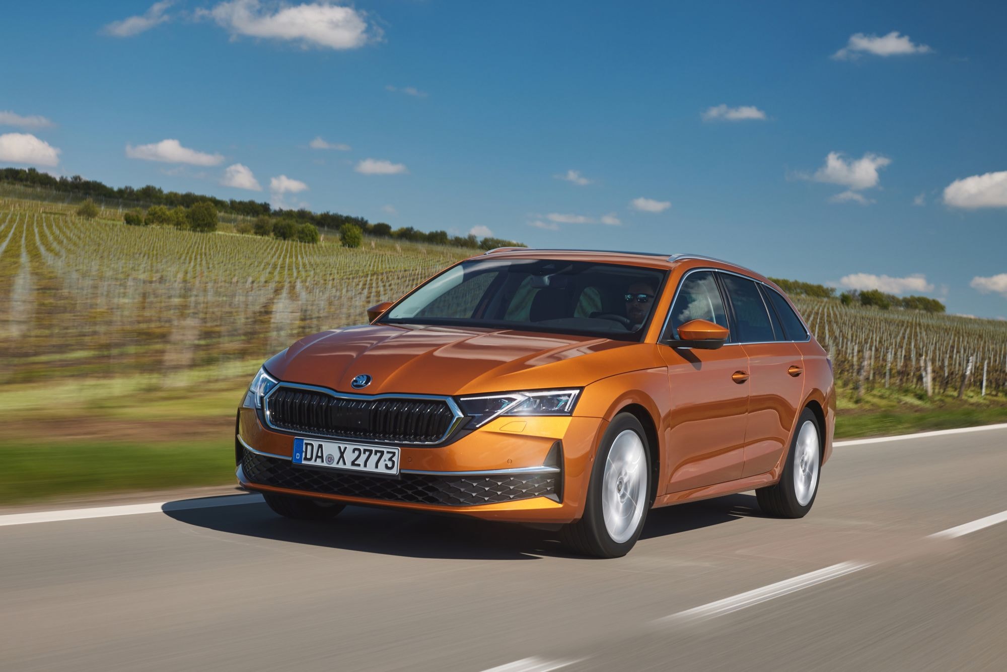 Vista trasera de un Skoda Octavia Combi naranja, muy atractivo en movimiento.