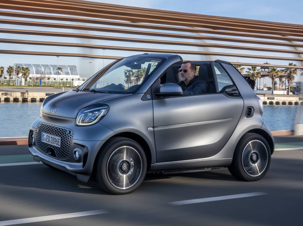 Smart EQ Fortwo Cabrio circulando, reflejo de movilidad urbana sostenible.