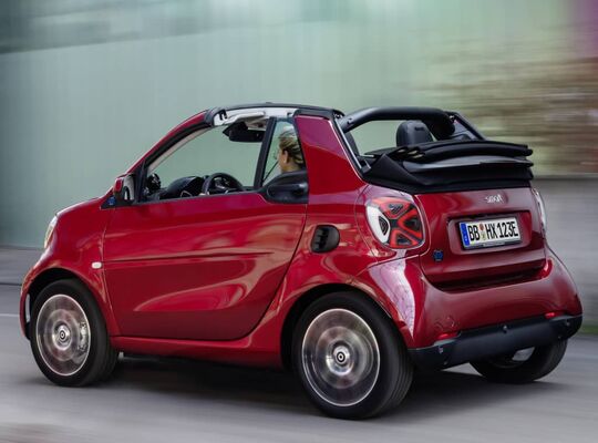 Smart EQ Fortwo Cabrio en movimiento, destacando su diseño lateral. Smart EQ Fortwo Cabrio en movimiento, destacando su diseño lateral.