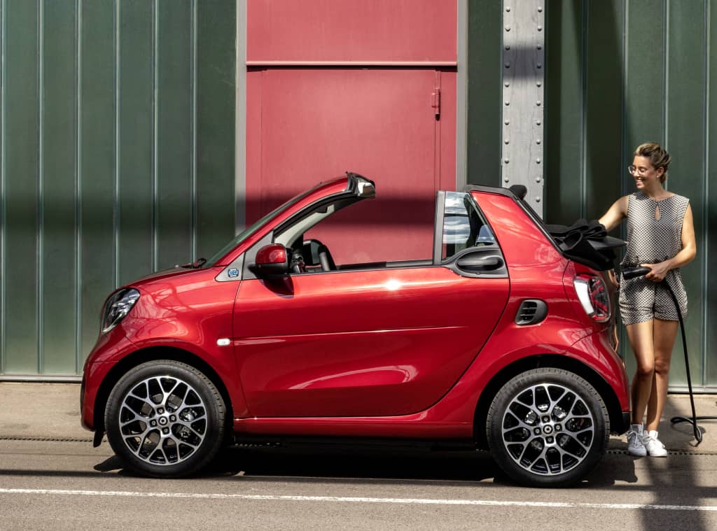 Imagen lateral del Smart EQ Fortwo Cabrio con una persona cargándolo.