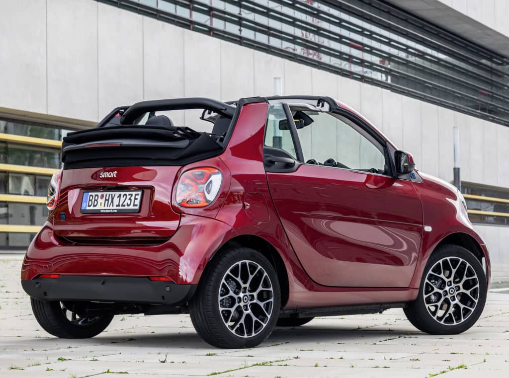 Trasera y lateral del Smart EQ Fortwo Cabrio con un edificio de fondo.