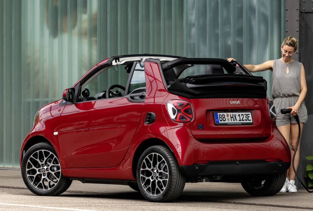 Vista trasera del Smart EQ Fortwo Cabrio con una persona apoyada.