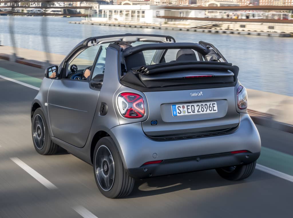Vista trasera del Smart EQ Fortwo Cabrio en carretera, con techo replegado.