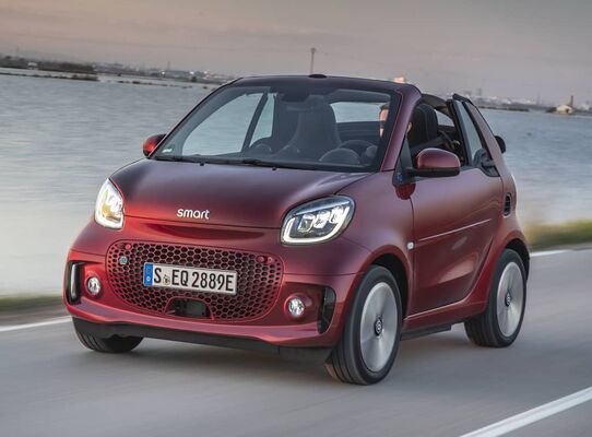 Smart EQ Fortwo Cabrio rojo en movimiento, destacando su techo. Smart EQ Fortwo Cabrio rojo en movimiento, destacando su techo.