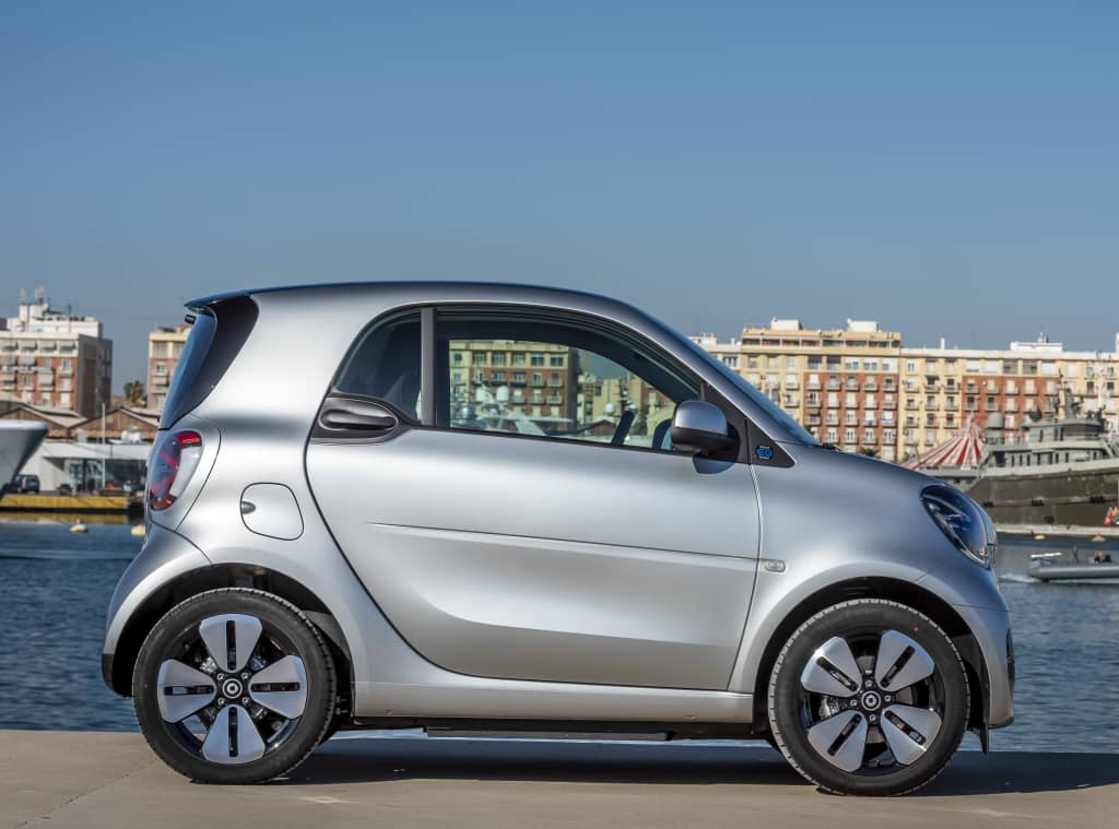 Vista lateral del Smart EQ Fortwo aparcado en un paisaje urbano.