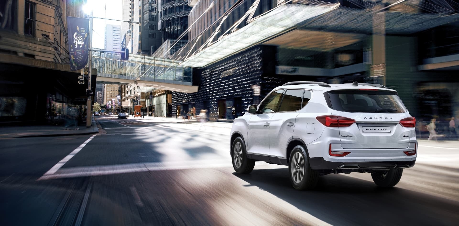 Vista trasera del SsangYong Rexton en movimiento por la ciudad, destacando su diseño y dinamismo.