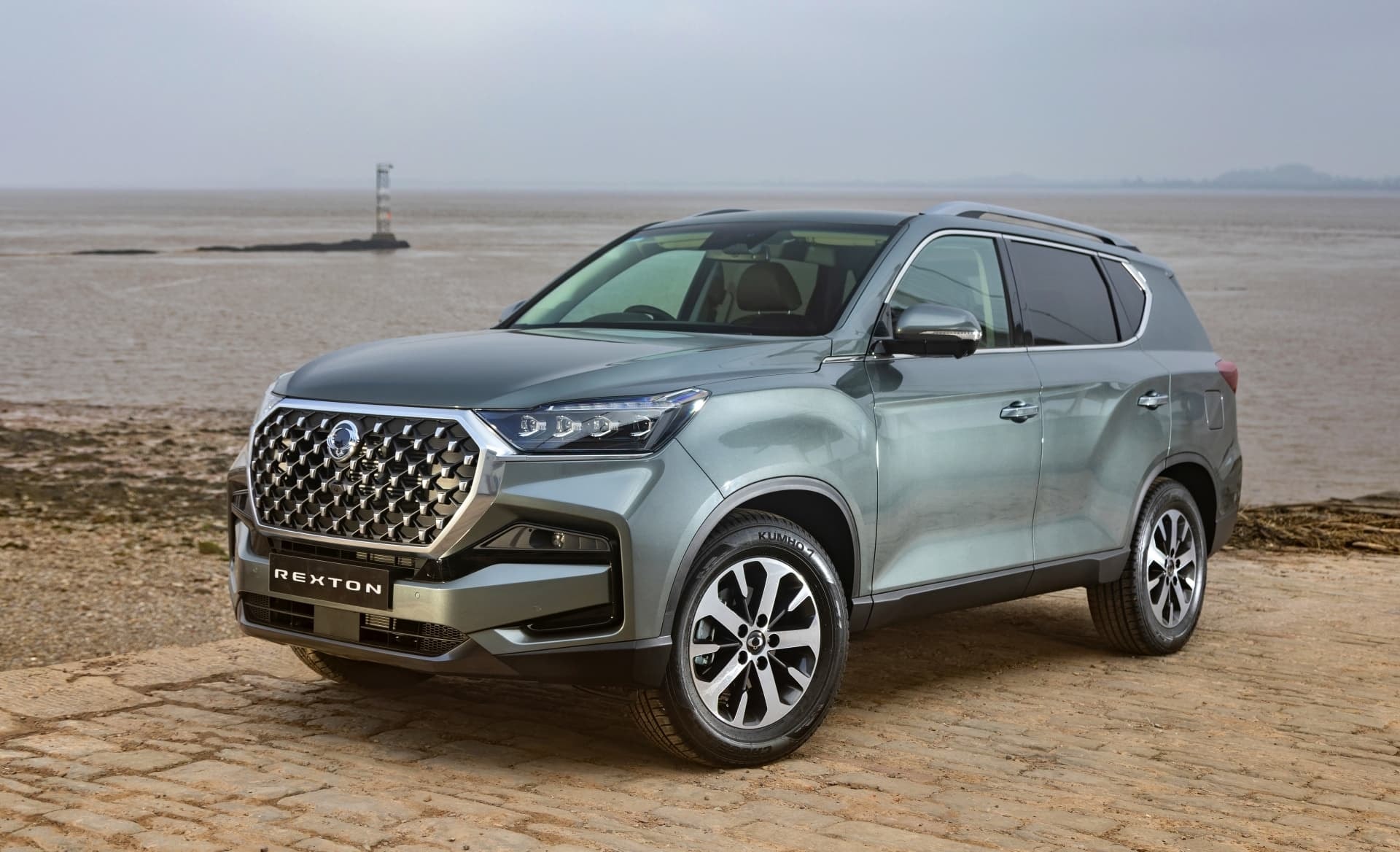 Rexton frente al mar, destacando su robusta parrilla.