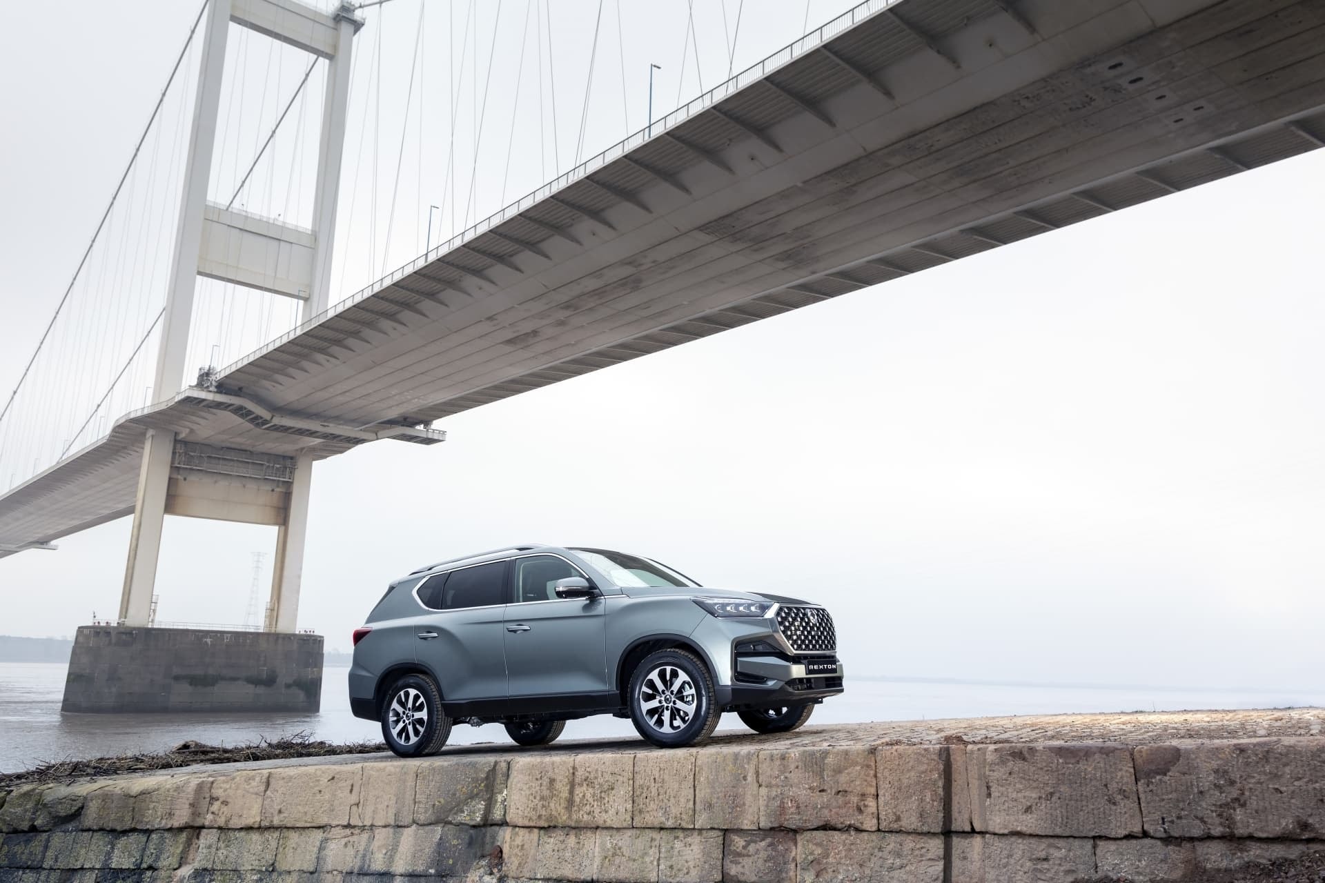 Vista lateral del SsangYong Rexton debajo de un puente, mostrando su perfil robusto.