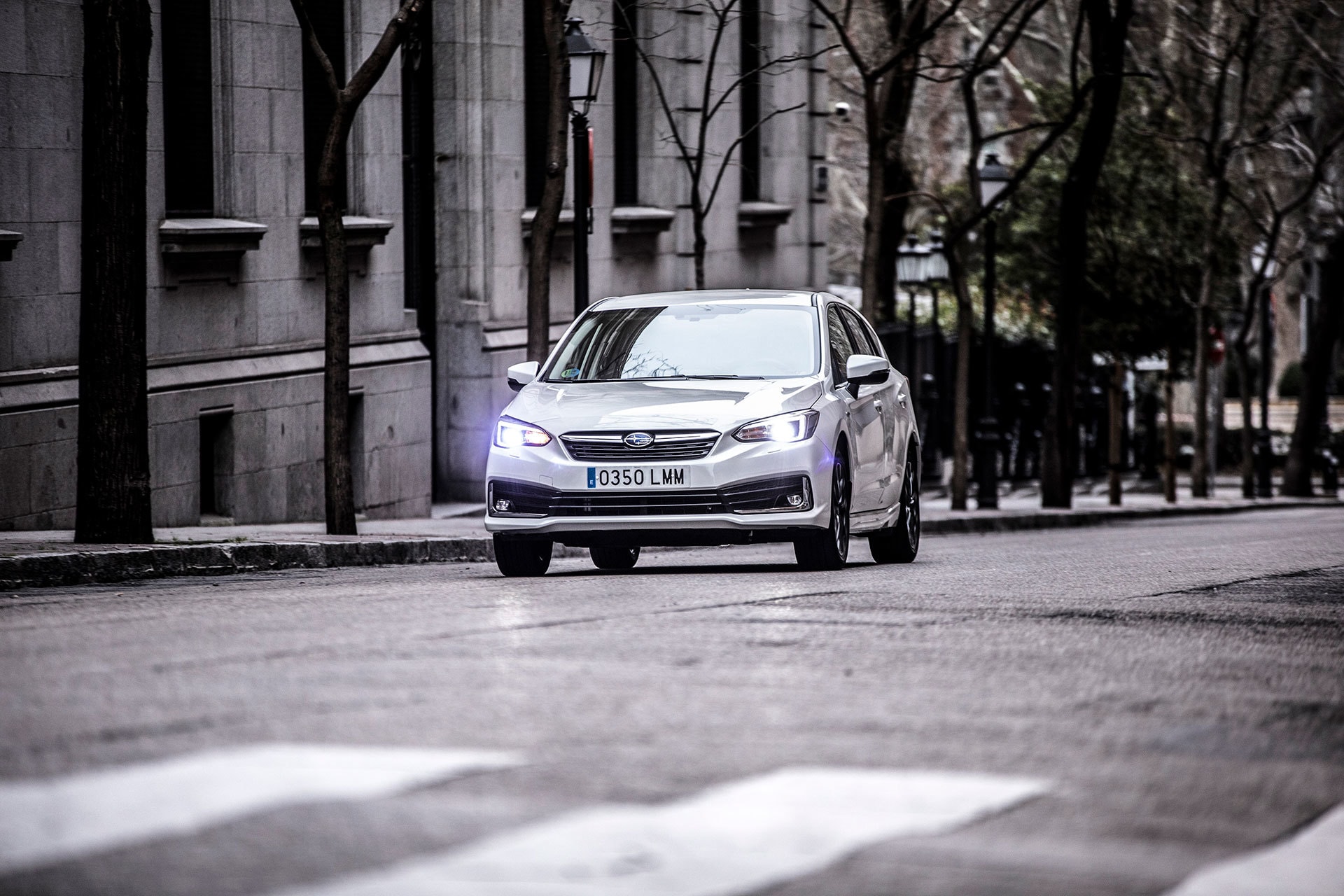 Subaru Impreza híbrido aproximándose, vista frontal en ambiente urbano.